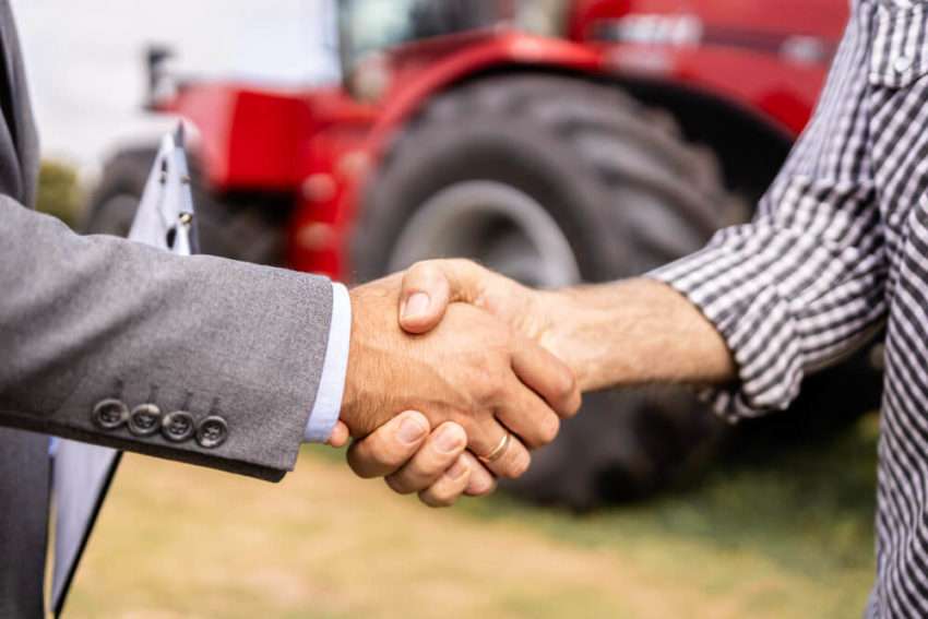 Buying new tractor agricultural machine Buyer and dealer handshake at tractor dealership
