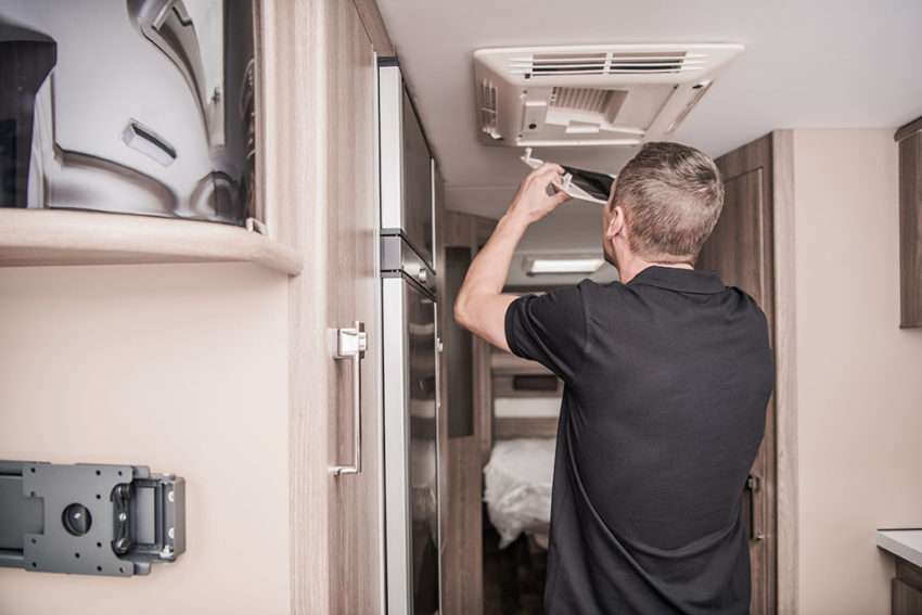 RVTechnician Replacing Air Condition Filter Inside Travel Trailer. Recreational Vehicles and Travel Industry.